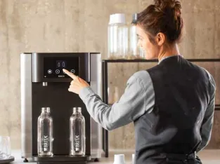 Frau bedient einen Wasserspender