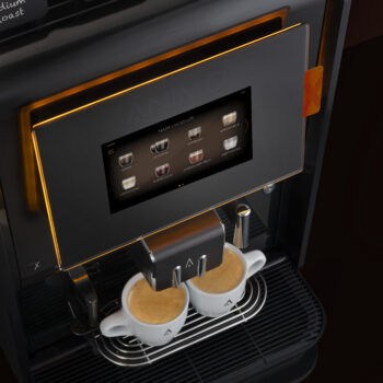 zwei volle Espressotassen unter einer Kaffeemaschine