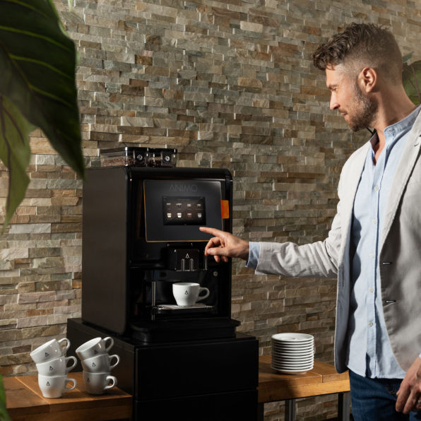 Mann drückt Knopf an einer kaffeemaschine